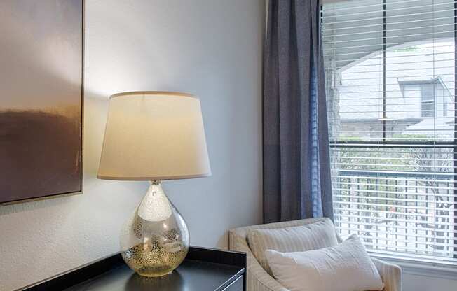 a bedroom with a chair and a dresser with a lamp on it