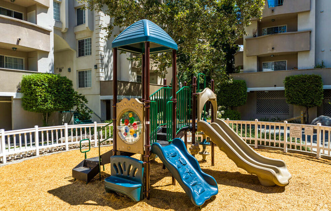 a playground with a swing set and slides in front of an apartment building