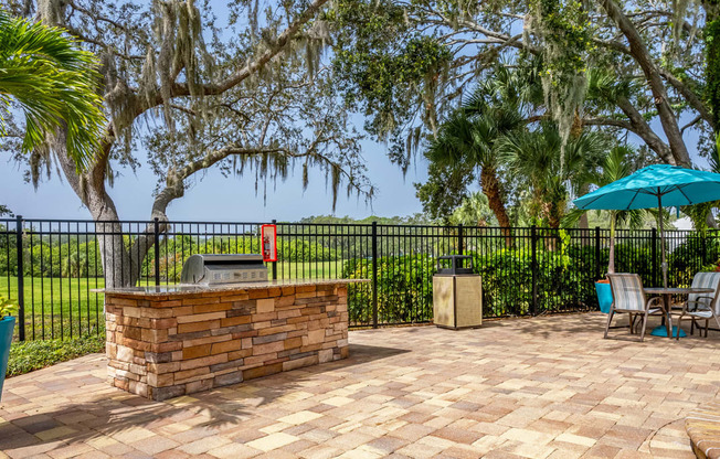 a patio with a grill and a table with chairs and an umbrella