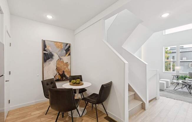 A dining room with a table and chairs and a painting on the wall.