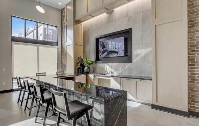 a kitchen with a bar with chairs and a tv on the wall