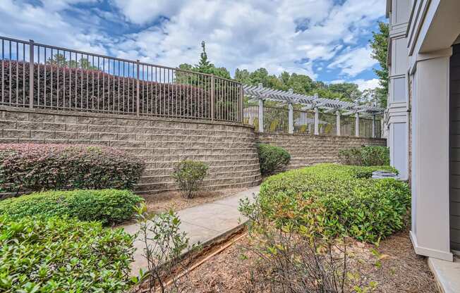 a brick retaining wall with a fence on top of it and a sidewalk