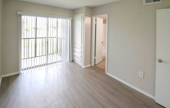 an empty living room with wood floors and a sliding glass door