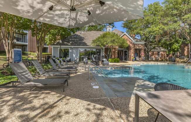 a swimming pool with chairs and umbrellas in front of a house at Lakeshore at Preston, Plano, 75093