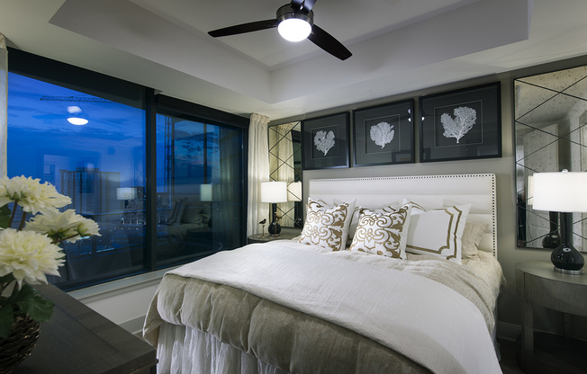 Bedroom featuring a large bed and dresser, recessed ceiling with a fan, full-width window, and white walls with a gray accent wall.
