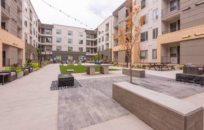an open area with benches and trees in the middle of an apartment complex