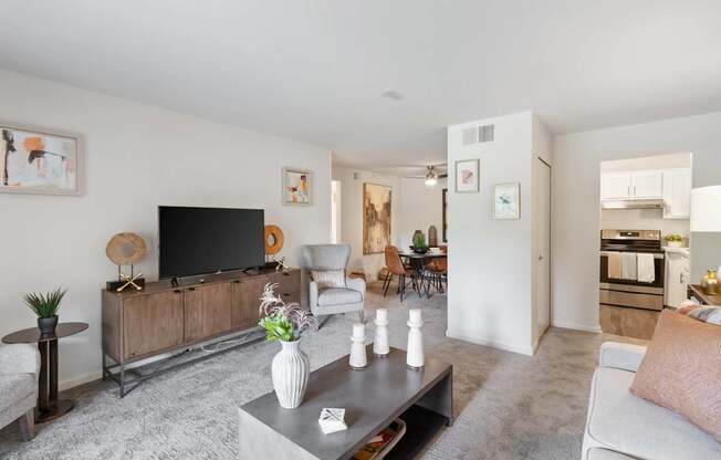 A modern living room with a grey carpet and a wooden entertainment center.