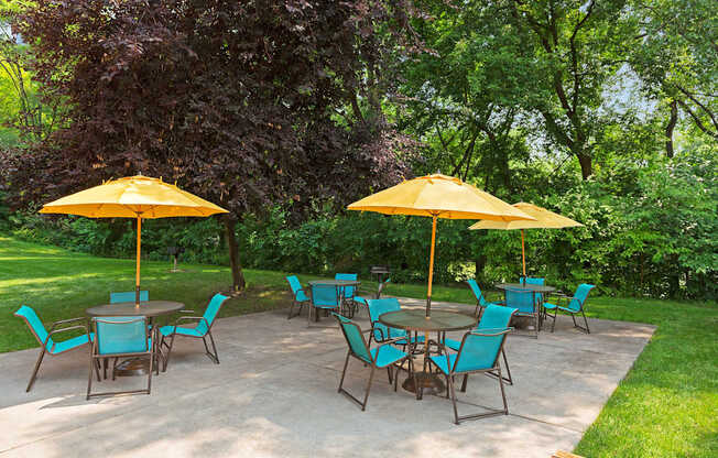 A patio with blue chairs and yellow umbrellas.
