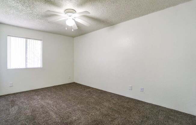 A room with a ceiling fan and carpeted floor.