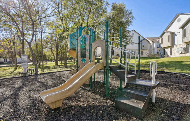 Our community playground with a slide, stairs and a climbing frame at On the Green apartments in Austin, TX