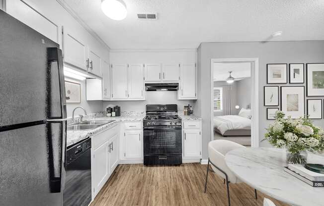 a kitchen with white cabinets and black appliances and a table