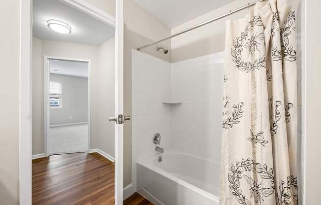 A bathroom with a shower and a wooden floor.