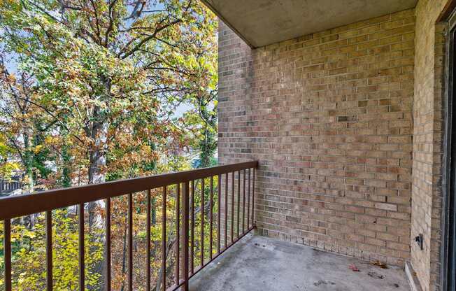 A balcony with a brick wall and a metal railing.