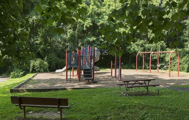 Playground surrounded by lush green landscaping at Trillium Apartments, Fairfax, 22031