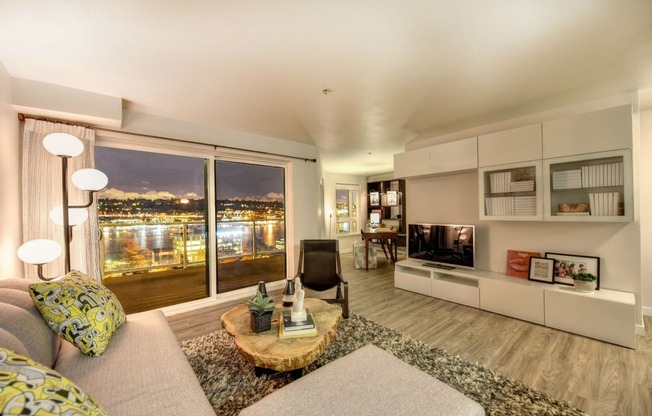 Living Room with Hardwood Inspired Floor, Gray Sofa, Television and Patio Door Leading to Night Sky View