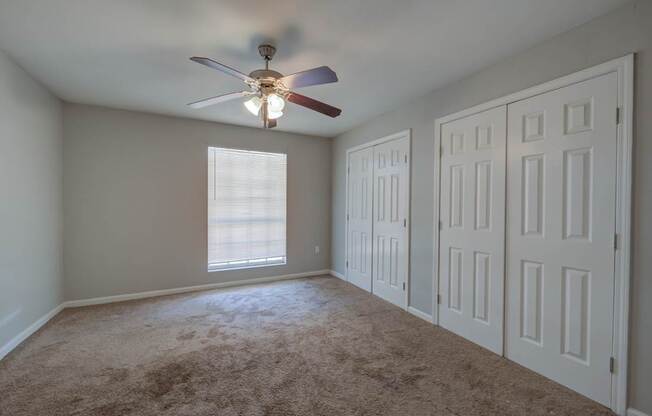 A room with a ceiling fan and carpeted floor.