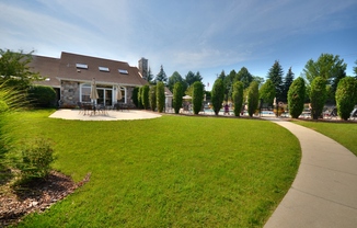 a large lawn in front of a clubhouse with a sidewalk