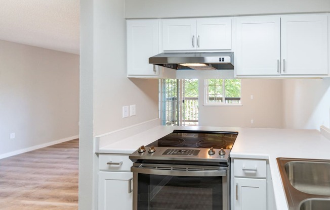 an empty kitchen with white cabinets and a stainless steel stove