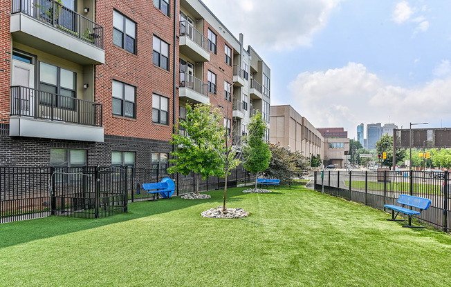 Dog Park with grassy area with benches and trees in front of an apartment building at The View at Old City, Philadelphia