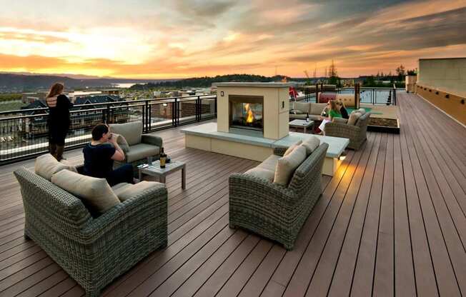 A couple is sitting on a couch on a wooden deck with a fireplace.