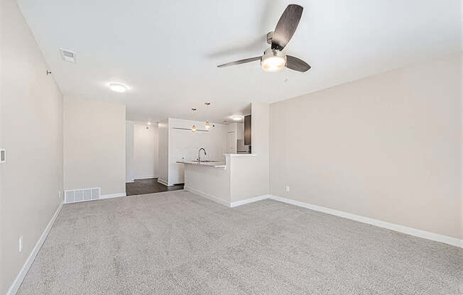 A spacious living room with a ceiling fan and carpeted floor at Copper Creek Apartment Homes, Maize, Kansas