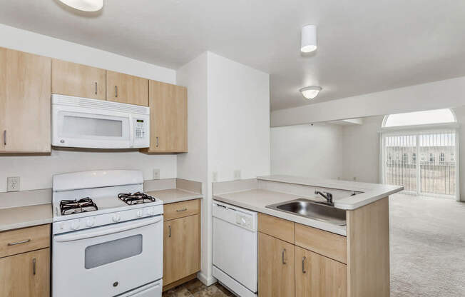 A kitchen with white appliances and wooden cabinets at Stoney Pointe Apartment Homes in Wichita, KS