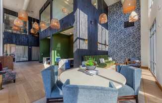 a communal area with a round table with blue chairs and a green couch in the background