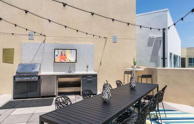 A patio with a table, chairs, and a grill.