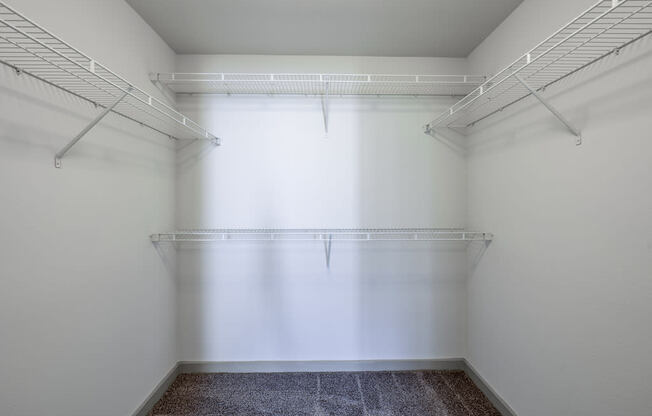 a walk in closet in a white room with a window