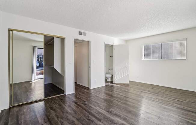 A large empty room with wooden floors and a large mirror on the wall.