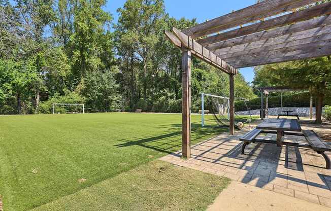 A wooden pergola is over a picnic table in a park.