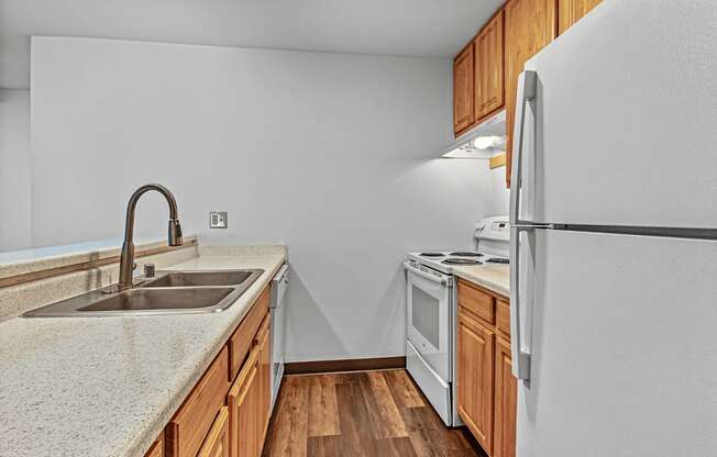A kitchen with a white fridge, sink and wooden cabinets.