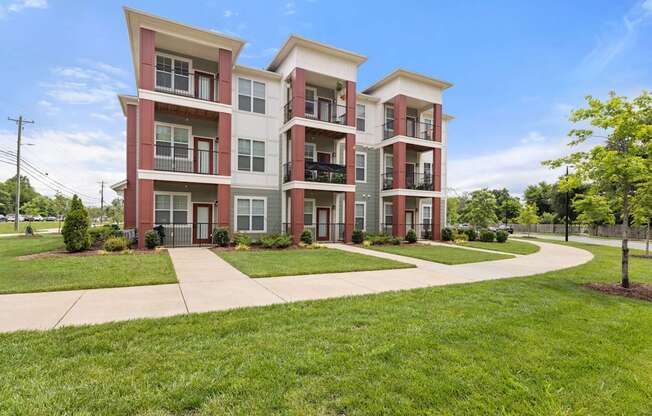 A red and white apartment building with a green lawn in front.