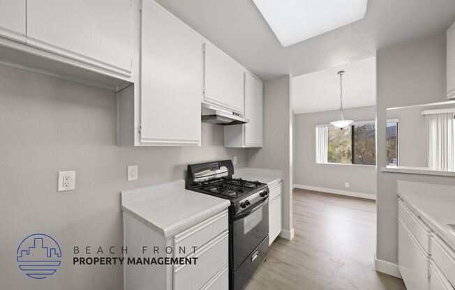 a kitchen with white cabinets and a stove and a window