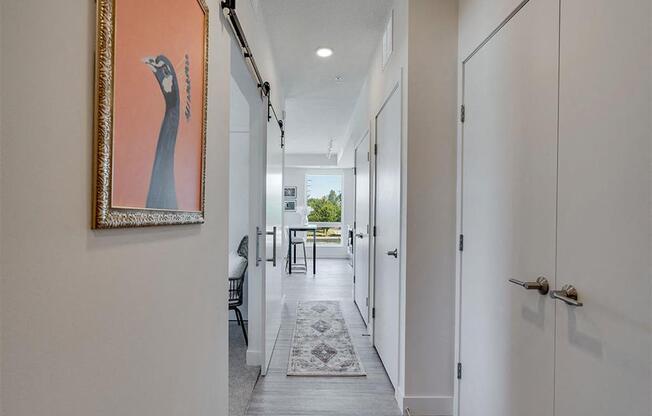 a long hallway with white doors and a painting on the wall