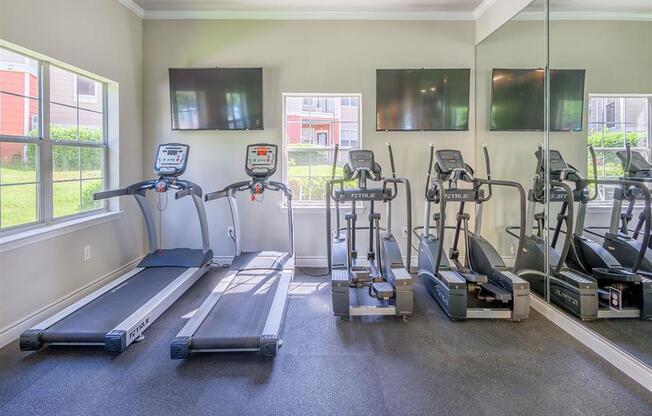 Premium fitness center with exercise machines, padded flooring, tall windows, and high ceiling at Evergreen at Mahan in Tallahassee, FL
