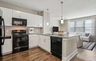 A modern kitchen with white cabinets and black appliances.