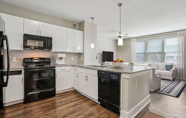 A modern kitchen with white cabinets and black appliances.