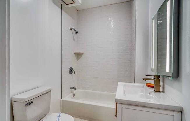 A white bathroom with a toilet, sink, and bathtub.
