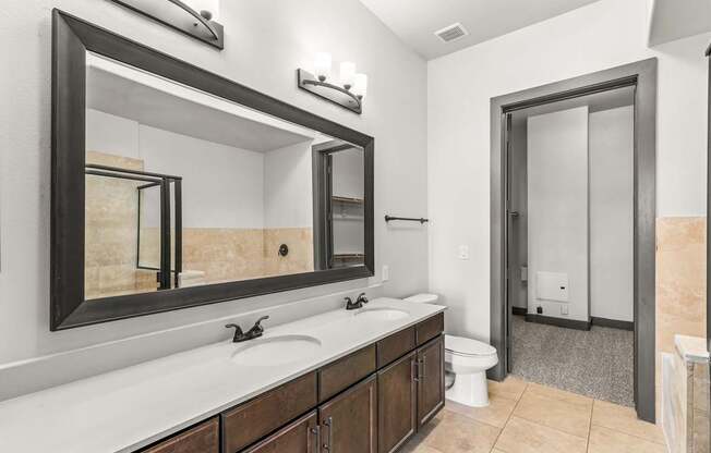 A bathroom with a toilet, sink, and mirror.