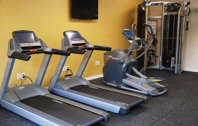 Fitness room with two treadmills, eliptical, and cable machine