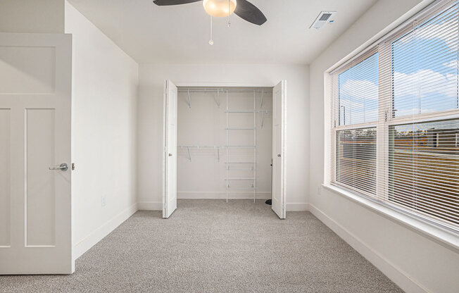 a bedroom with a large window and a walk in closet  at Signature Pointe Apartment Homes, Athens, AL, 35611