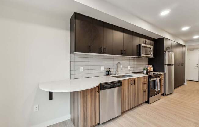A modern kitchen with a white countertop and stainless steel appliances.