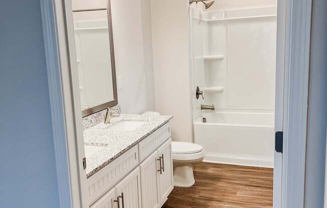 A bathroom with a toilet, sink, and mirror.