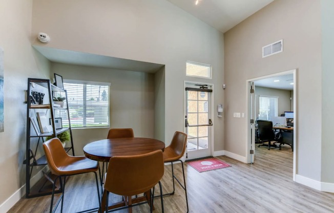 a dining area with a round table and four orange chairs