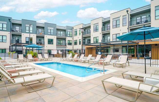 A lounge pool surrounded by several lounge chairs and umbrellas for shade.
