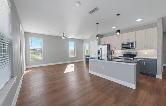 A spacious kitchen with wooden floors and modern appliances.