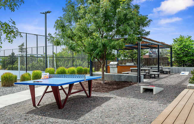 A blue table is in the middle of a gravel area.