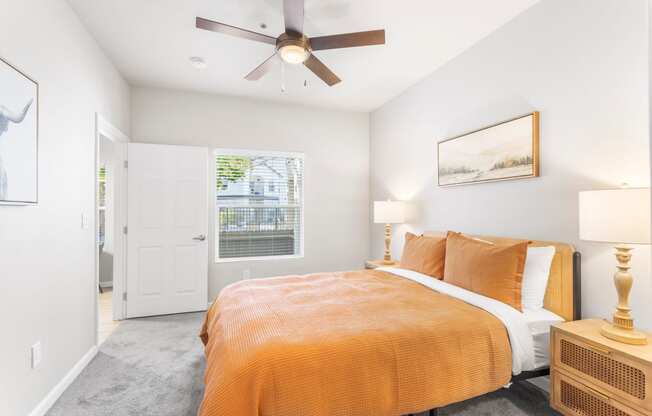 a bedroom with an orange bed and a ceiling fan