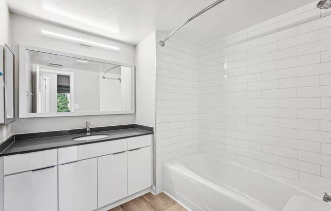 a white bathroom with a tub and a sink and a mirror